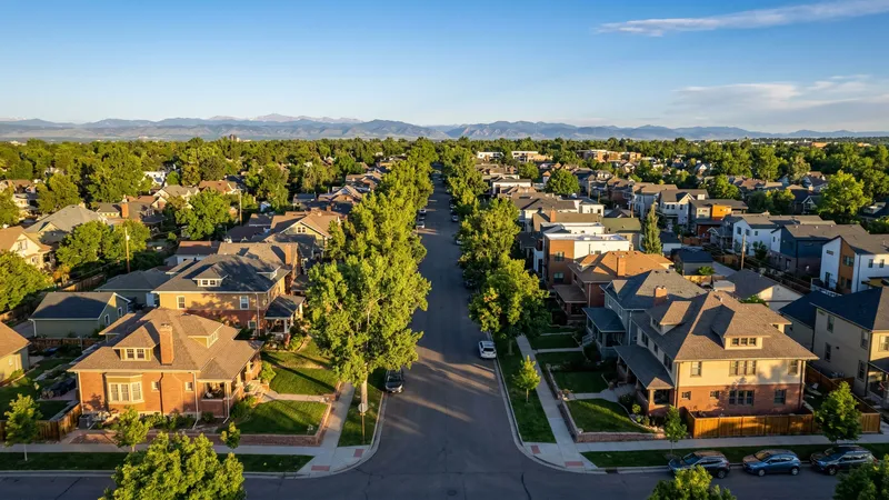 Tree-lined Denver residential street with freshly painted Craftsman homes and Front Range mountain view